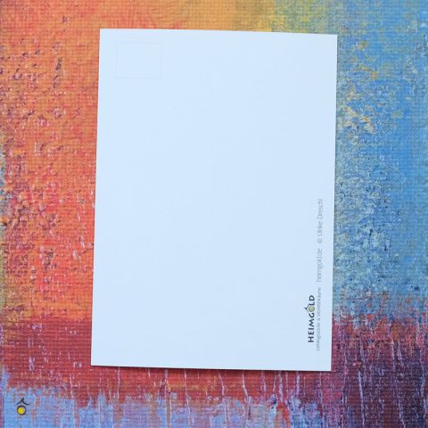Zu sehen ist die weiße Rückseite der Postkarte, die auf einem bunten Hintergrund liegt, mit dem Logo von Heimgold, Websiteadresse und copyright am Rand platziert