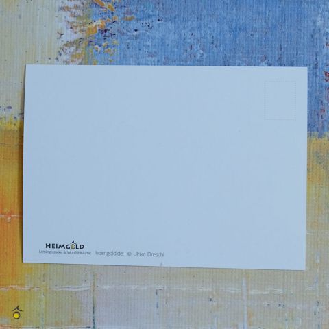 Zu sehen ist die weiße Rückseite der Postkarte, die auf einem bunten Hintergrund liegt, mit dem Logo von Heimgold, Websiteadresse und copyright am Rand platziert